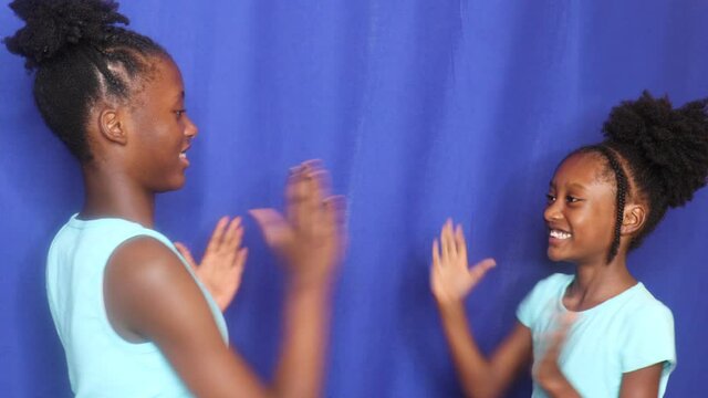 African American Girls playing hand games smiling laughing having fun blue studi curtain background