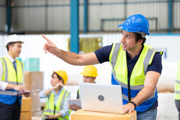 engineer or factory worker using laptop computer, talking and pointing to something