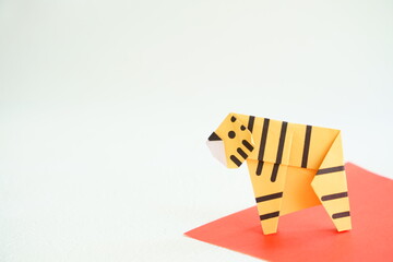 白い背景に赤い敷物の上に折り紙の横向きの黄色い虎