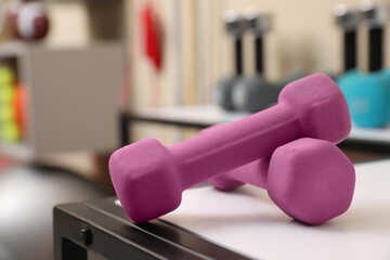 Pink dumbbells on white table indoors, closeup. Sports equipment