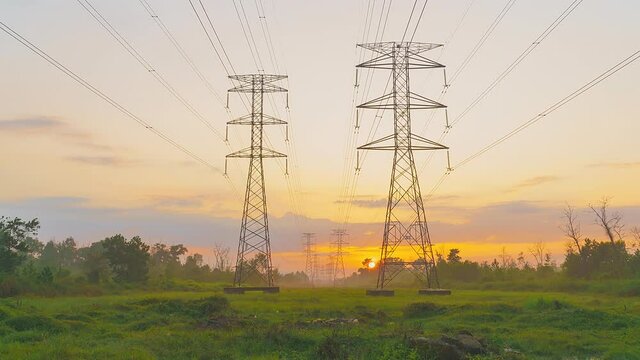4k time lapse of sunrise with transmission electricity steel pylon tower in the middle of the field.
