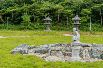 Obraz premium Dry stone circled water fountain with two large stone carved lanterns in background.