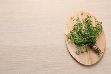 Bunch of aromatic thyme on wooden table, top view. Space for text