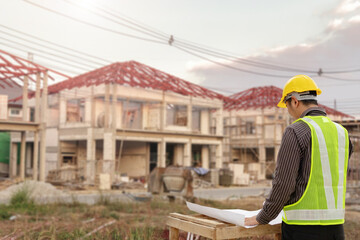 Fototapeta premium young professional engineer in protective helmet and blueprints paper at the house building construction site
