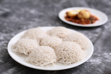 Kerala foods- homemade delicious breakfast- steamed rice noodles string hoppers  known as idiyappam, served with egg roast curry.