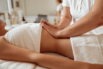 Masseuse hands massaging woman abdomen at wellness center