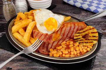 Grilled gammon egg and chips meal with baked beans and pineapple fruit ring
