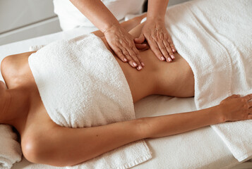 Fototapeta na wymiar Female client receiving stomach massage in spa salon