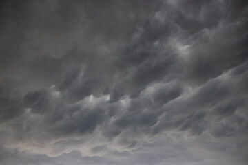 A wide angle cloudscape shot of dramatic clouds in a dark and stormy sky, a thunderstorm with...