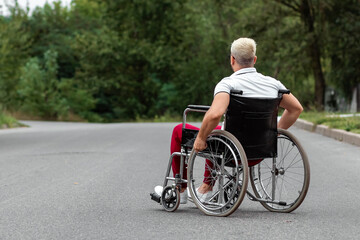 A disabled man sits in a wheelchair on the street. The concept of a wheelchair, disabled person, full life, paralyzed, disabled person, health care.