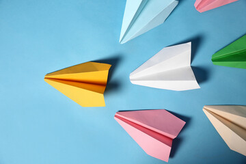 Yellow paper plane leading others on turquoise background, flat lay. Diversity concept