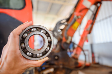 Close-up shot of mechanic and wheel bearings and large wheel hubs of the tractor large vehicles The...