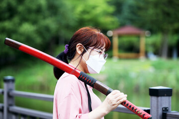 Korean woman practicing kendo in a hi-dong kendo pose with a sword.