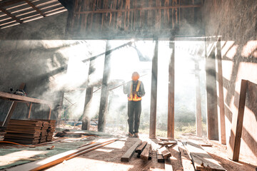 Young Asian carpentry worker in a workshop Work on the roof structure of a wooden house at a...