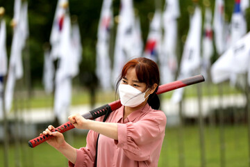 Korean woman practicing kendo in a hi-dong kendo pose with a sword