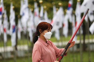 Korean woman practicing kendo in a hi-dong kendo pose with a sword