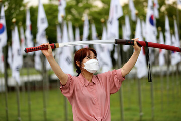 Korean woman practicing kendo in a hi-dong kendo pose with a sword