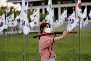 Korean woman practicing kendo in a hi-dong kendo pose with a sword