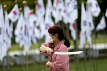 Korean woman practicing kendo in a hi-dong kendo pose with a sword