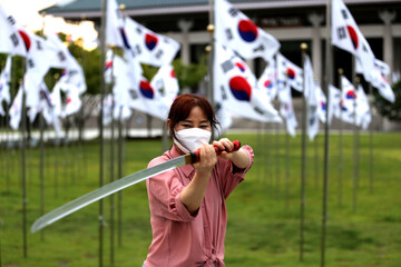 Korean woman practicing kendo in a hi-dong kendo pose with a sword