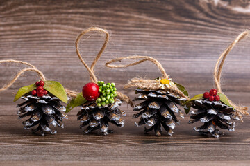 Handmade Christmas tree toys made of pine cones, decorated with natural materials, against background of cut tree. Decorations with suspension of hemp twine. New Year and Christmas concept.