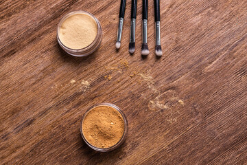 Mineral powder for face and a brushes for powder and visage on wooden background with copy space. Eco friendly and organic cosmetics.