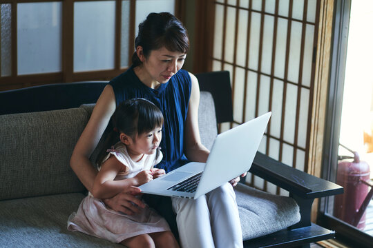 パソコンでインターネットをしている母と娘