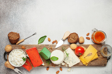 Assortment of different cheese types - brie, blue, green and red pesto on cutting board. Food background. Top view. Flat lay