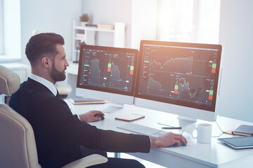 Serious young man in shirt and tie analyzing data on the stock market while working in the office