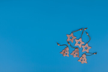 New Year and Christmas wooden toys on blue background. Laser cut wooden Christmas tree and stars figurines. Postcard composition with free space for text. New Year and Christmas concept.