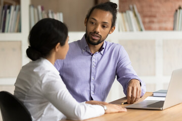 Two multi racial colleagues, Indian female African man working on collaborative project at...