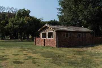 Obraz premium The old brick building set up on the grass. It is near by a lot of tree.