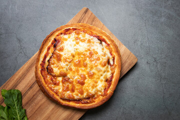 Delicious gourmet pizza with guanciale on wooden board with black table background. Homemade delicious pizza. Top view and copy space.