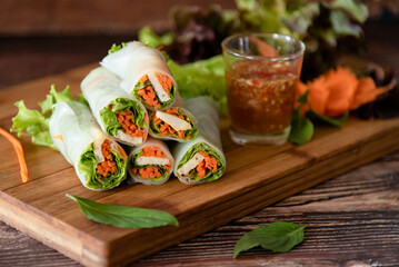 Closed-up fresh spring rolls stuffed pork, lettuce and carrot, Thai traditional food with spicy sauce