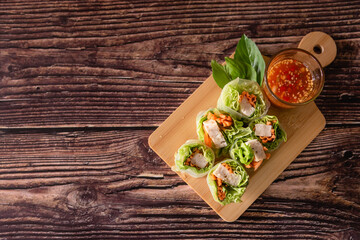 Top view of Asian fresh spring rolls with pork and shrimp, serve with spicy sauce, Thai traditional food on wooden background 