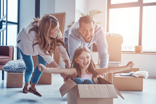 Cheerful young family smiling and unboxing their stuff while moving into a new apartment