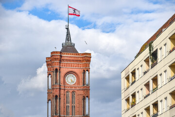 clock tower of the red town hall in berlin and residential buildings