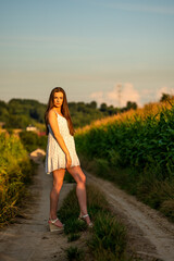 Young beautiful woman in white dress in corn field.