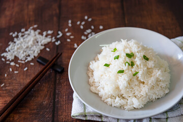 streamed rice on white plate at wooden background 