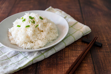 streamed rice on white plate at wooden background 