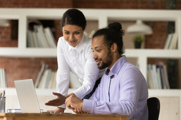 African intern sit at desk listens to female Indian mentor tells about task, explain company app,...