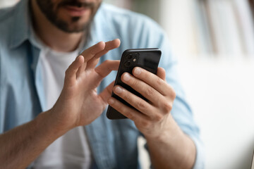 Close up view male hands holds smart phone spend time online use mobile application. Client of...