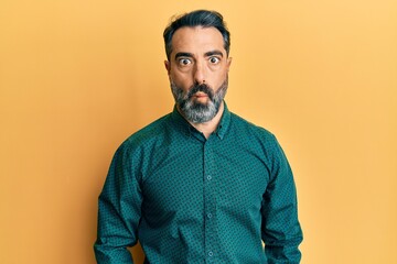 Middle age man with beard and grey hair wearing business clothes making fish face with lips, crazy and comical gesture. funny expression.