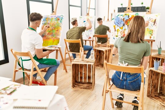 Group of people sitting on back view drawing at art studio.