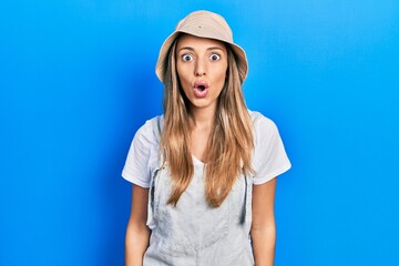 Beautiful hispanic woman wearing explorer hat scared and amazed with open mouth for surprise, disbelief face