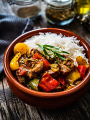 Roast pork with jasmine rice and vegetables in bowl on wooden table
