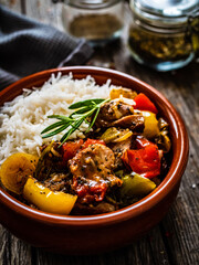 Roast pork with jasmine rice and vegetables in bowl on wooden table
