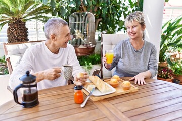 Senior caucasian couple smiling happy having breakfast at the terrace.