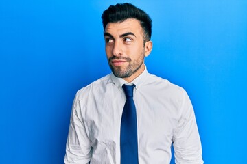 Young hispanic man wearing business clothes smiling looking to the side and staring away thinking.