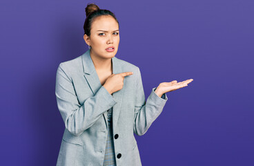 Young hispanic girl pointing open palm with finger clueless and confused expression. doubt concept.